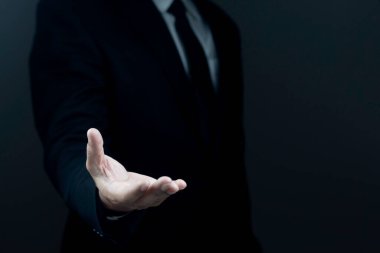 Takım elbiseli bir erkek, arka planda bir el hareketi gösteriyor. Talep kavramı, iflas, yakın çekim.