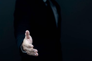 Takım elbiseli bir erkek işadamı elini uzatıyor ve arka planda bir el hareketi gösteriyor. Talep kavramı, tokalaşma.