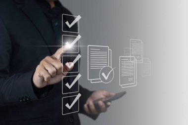 Koyu arkaplan üzerindeki sanal belge dosyalarının telefon ve denetim listesini kullanan işadamı.
