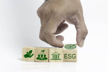 Sürdürülebilir yaşam ve ESG kavramları. Bir el, beyaz arka planda sürdürülebilirlik için yenilenebilir enerji kullanımını temsil eden sembollü bir küp alıyor..