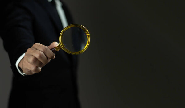A man is holding a magnifying glass and looking at something. Concept of curiosity and investigation