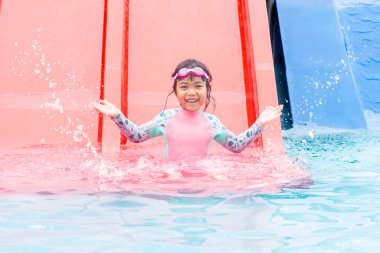 Şirin Asyalı kız gülüyor, eğleniyor ve su parkında oynamaktan zevk alıyor..