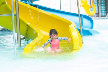 Şirin Asyalı kız gülüyor, eğleniyor ve su parkında oynamaktan zevk alıyor..