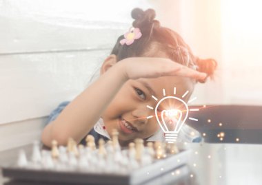 Satranç oynayan ve ampul ikonu olan bir kız. Yaratıcılık ve fikir kavramı.