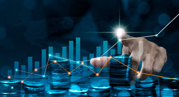 Businessman trading stock on virtual screen with foreground stack of coins. Growth business concept.