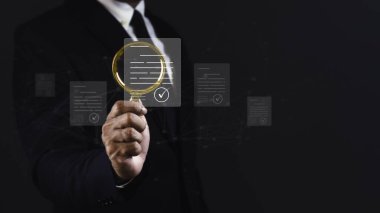 İş adamı koyu arkaplana karşı sanal ekran belge yönetimi ile büyüteç kullanıyor.