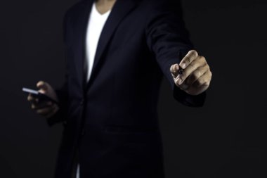 İş adamı karanlık arka plana karşı stil kalem ve akıllı telefon kullanıyor.