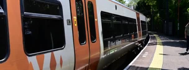 ワイドスクリーン電気鉄道のパノラマの変圧器ビデオ 通勤線の英語の農村駅を通過する列車 イギリス中西部 イギリスの鉄道 — ストック動画