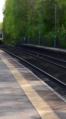 Birmingham 'ın banliyölerinde demiryolu ağı yolcusu banliyö treni. Batı Midlands, İngiltere. Tren geliyor, gidiyor, kırsal tren istasyonundan geçiyor..