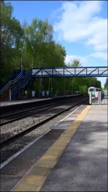 Birmingham 'ın banliyölerinde demiryolu ağı yolcusu banliyö treni. Batı Midlands, İngiltere. Tren geliyor, gidiyor, kırsal tren istasyonundan geçiyor..