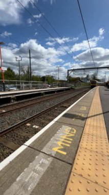 Birmingham 'ın banliyölerinde demiryolu ağı yolcusu banliyö treni. Batı Midlands, İngiltere. Tren geliyor, gidiyor, kırsal tren istasyonundan geçiyor..