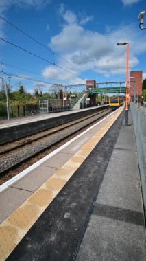 Birmingham 'ın banliyölerinde demiryolu ağı yolcusu banliyö treni. Batı Midlands, İngiltere. Tren geliyor, gidiyor, kırsal tren istasyonundan geçiyor..