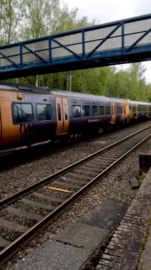 Birmingham 'ın banliyölerinde demiryolu ağı yolcusu banliyö treni. Batı Midlands, İngiltere. Tren geliyor, gidiyor, kırsal tren istasyonundan geçiyor..