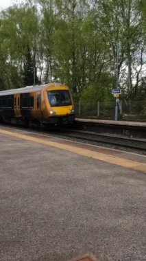 Birmingham 'ın banliyölerinde demiryolu ağı yolcusu banliyö treni. Batı Midlands, İngiltere. Tren geliyor, gidiyor, kırsal tren istasyonundan geçiyor..