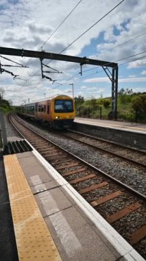 Birmingham 'ın banliyölerinde demiryolu ağı yolcusu banliyö treni. Batı Midlands, İngiltere. Tren geliyor, gidiyor, kırsal tren istasyonundan geçiyor..