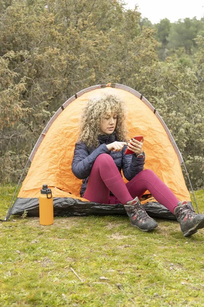 Кудрявые Светлые Волосы Альпинистские Лагеря Оранжевой Палаткой Смартфоном — стоковое фото