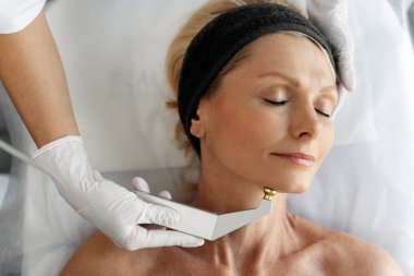 Kapalı gözlü bir kadın portresi güzellik salonunda mikro cilt bakımı yaptırıyor. Doktor müşteriyle çalışıyor. 