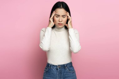 Kafası ağrıyan, sıkıntıları olan üzgün bir kadının portresi. Pembe arka planda kapalı stüdyo çekimleri 