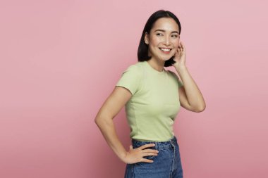 Mutlu iyimser kızın portresi gülümseyen, başka tarafa bakan, eğlenen. Pembe arka planda kapalı stüdyo çekimleri 