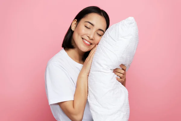Photo portrait of gorgeous girl hugging pillow with closed eyes isolated on pink coloured background. Bedtime concept
