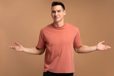 Bilmiyorum, kimin umurunda. Kafası karışmış hippi adam hiç bir fikri olmadan omuz silkiyor, el kaldırıyor. Bej arka planda izole edilmiş kapalı stüdyo çekimleri 