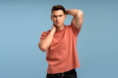 Ciddi bir ifadeyle kameraya bakan özgüvenli bir adamın portresi. Gülümsemeyen kararlı bir adam. Mavi arka planda kapalı stüdyo çekimi 