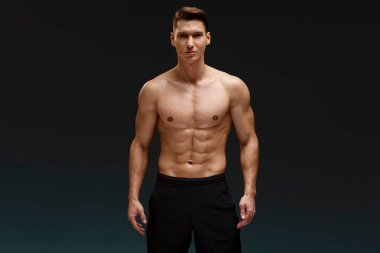 Beyaz tenli, çıplak, seksi bir adam. Stüdyoda, duvarın arkasında poz veriyor. Spor ve figür kavramı 