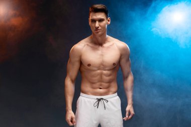 Mükemmel bedeninin tadını çıkaran yakışıklı bir adamın fotoğrafı. Koyu renkli arka planda izole edilmiş boş bir alan. 