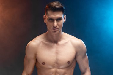 Çekici, çekici bir adamın portresi. Kaslı, çıplak gövdesini gösteriyor. Siyah arka planda izole edilmiş kameraya bakıyor. 