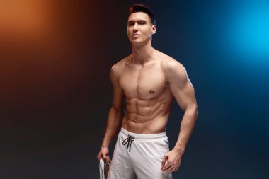 İp atlayan ve kameraya bakan ciddi bir sporcu. Sağlıklı yaşam tarzı kavramı. Siyah arka planda çıplak gövdesi olan genç atletik bir adam. Stüdyo çekimi 