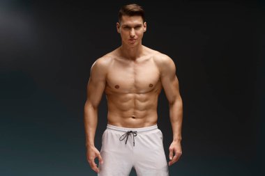 Üstsüz vücut pozu veren yakışıklı maço adamın fotoğrafı ve siyah arka planda dikkatlice izole edilmiş bir kamera görüntüsü. 