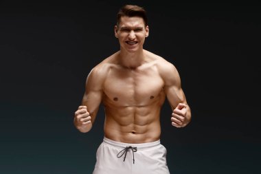 Siyah arka planda yapayalnız dururken kameraya bakıp çığlık atan yakışıklı bir adamın portresi. Genç hippi çıplak duruyor. Kaslı ve erkeksi bir adam. Mükemmel erkek güzelliği. 