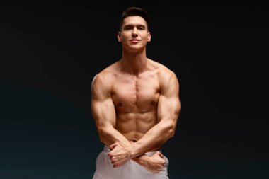 Üstsüz vücut pozu veren yakışıklı maço adamın fotoğrafı ve siyah arka planda dikkatlice izole edilmiş bir kamera görüntüsü. 