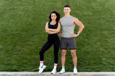 Full length view of the young street fashion couple posing in front of green wall. Sport and recreation concept 