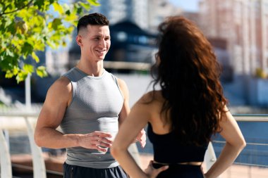 Smiling couple talking after sportive training outdoors. Fitness, sport, friendship and lifestyle concept. Stock photo