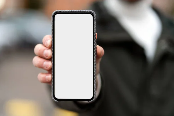 Man showing phone screen outdoors. Blank screen, space for advertising.