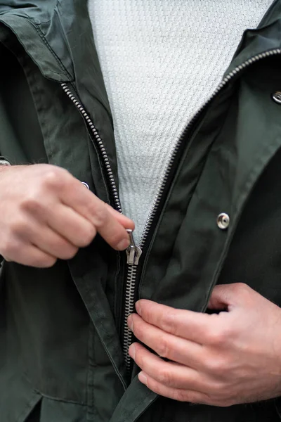 Young man wearing a jacket, man holding a jacket zip.