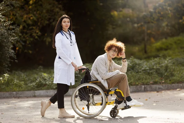 Красива Медсестра Носить Втомленого Пацієнта Молодого Чоловіка Інвалідному Візку Прогулянка — стокове фото
