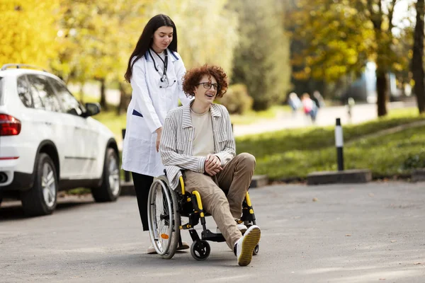 Догляд Молода Жінка Лікар Яка Носить Свого Пацієнта Інвалідному Візку — стокове фото