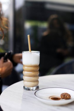 İçkili bir bardak masanın üstünde. Bir bardak latte ya da cappuccino, yakın çekim, seçici odak.