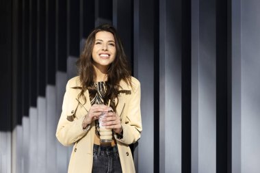 Gri bir duvarın arkasında duran güzel bir kadının portresi, güneş onun üzerinde parlıyor. Genç bir kız elinde içkiyle bardağı tutuyor, gülümsüyor, başka tarafa bakıyor..