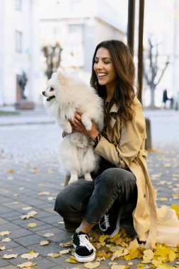 Genç bir kız sokakta, kollarında güzel bir köpek tutuyor. Neşeli bir kız evcil hayvanını tutar, bakar.