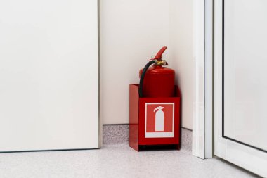 Odanın köşesinde kırmızı yangın söndürücü duruyor. Hayat güvenliği kavramı.