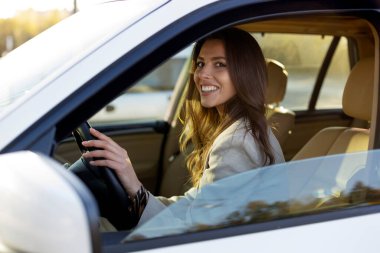 Çekici genç esmer kız araba kullanıyor. Genç bir kadın rahat bir arabada araba kullanıyor..