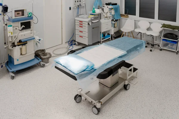 stock image Sterile room, operating room. In the center is an operating table covered with a diaper. Modern, equipped operating room, important equipment for maintaining vital activity of the body during surgery.