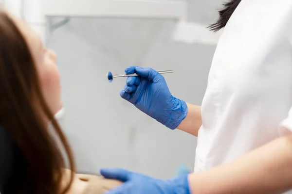 Dentist starts treating the patient\'s teeth. Closeup view, doctor holding dental instrument.