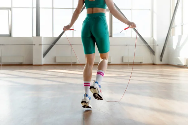 Fit girl jumping rope in gym, selective focus on buttocks. Workout concept, fit body