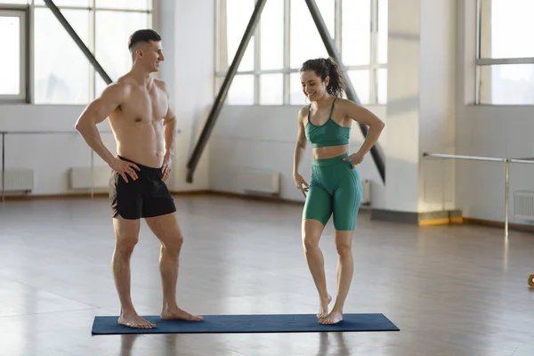 stock image Smiling hispanic guy and girl doing sports in gym, talking. Fit young couple exercising