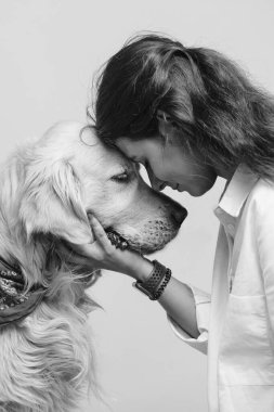 Mavi arka planda izole edilmiş, sevimli, gülümseyen bir kadının siyah beyaz portresi. En sevdiği köpek, golden retriever