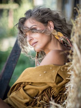 Uzun bacaklı ve kahverengi çizmeli şehvetli kız çiftlikteki ahşap sandalyede oturuyor. Batı sahnesinde güzel vücutlu güzel bir kız. Uzun bacaklı, sütyenli ve kıvırcık saçlı bir model.